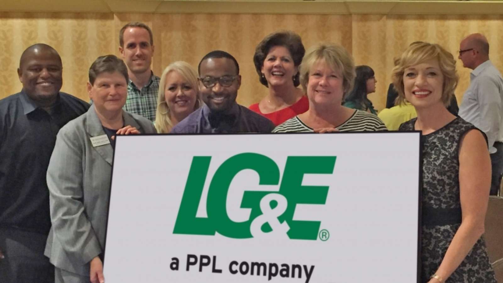 LG&E employees at a community event holding an LG&E sign