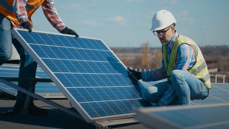 workers installing a solar panel on a roof