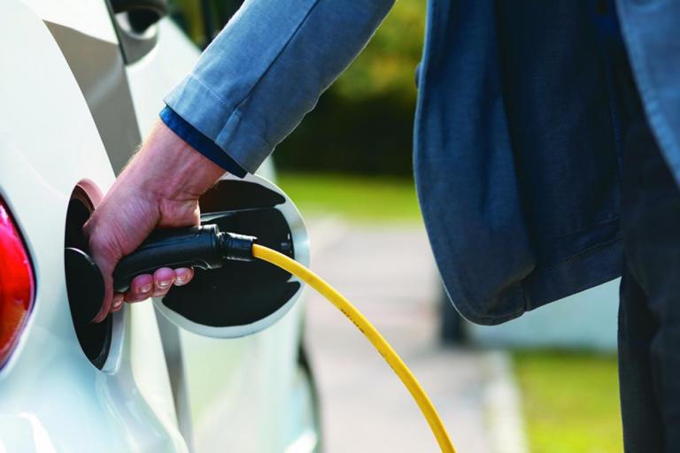 man inserting charger into electric vehicle